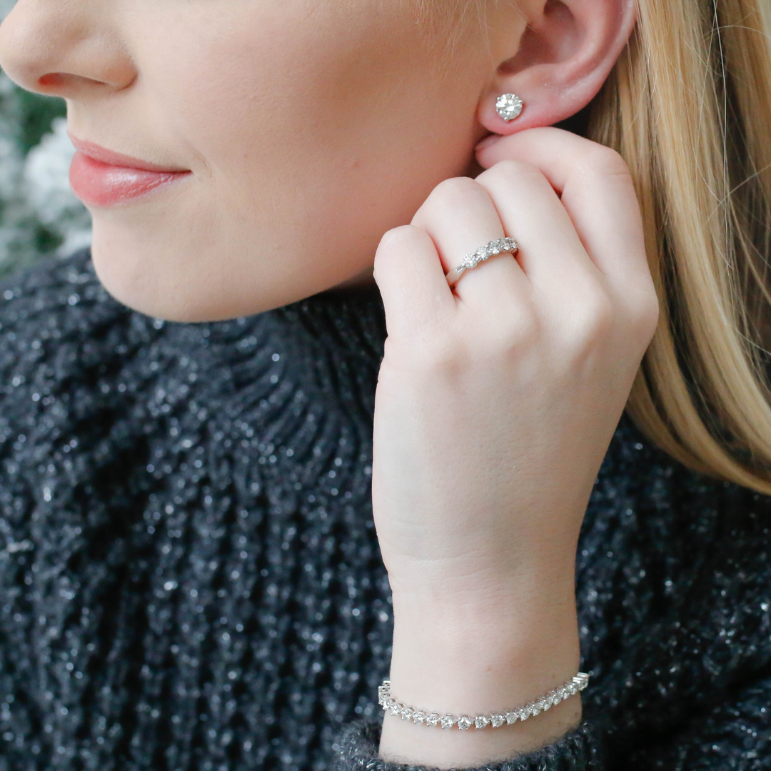 Woman wearing Hearts on Fire diamond stud earrings, rings, and bracelet