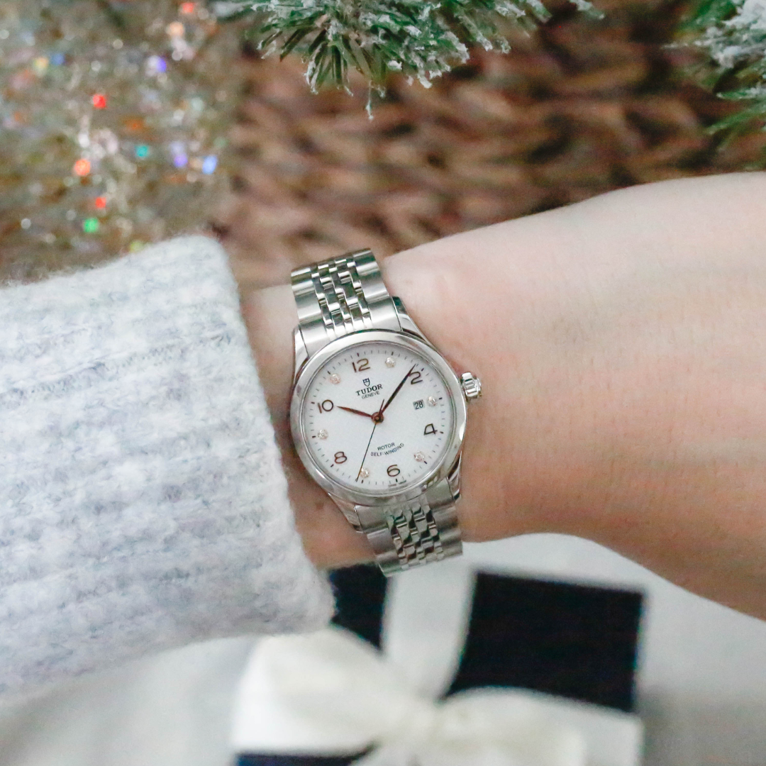 A Tudor timepiece on a female's wrist by a Christmas tree